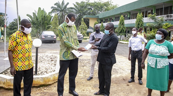 Mr John Saighoe receiving one of the Themometer Guns from the Vice Chancellor